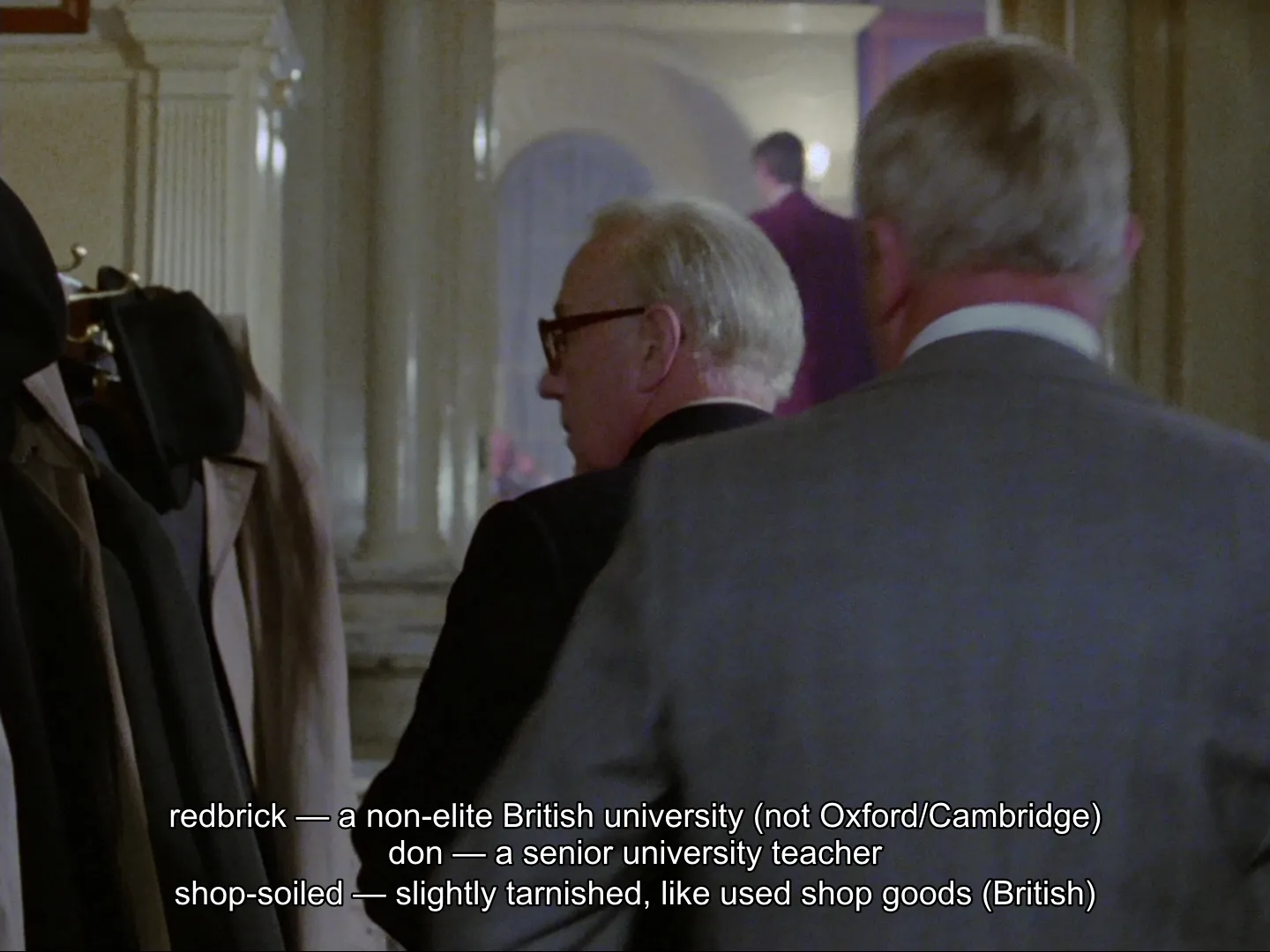Three Explainer definitions stacked along the bottom of a scene from Tinker, Tailor, Soldier, Spy (1979): “redbrick — a non-elite British university (not Oxford/Cambridge)”, “don — a senior university teacher”, and “shop-soiled — slightly tarnished, like used shop goods (British)”